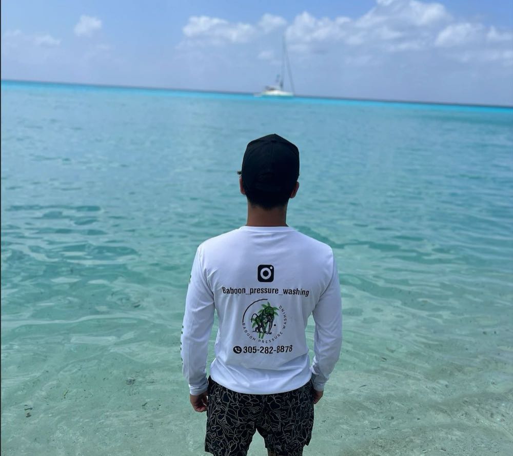 Michael Babun from behind, wearing a Baboon Pressure Washing long-sleeve shirt with the logo and phone number