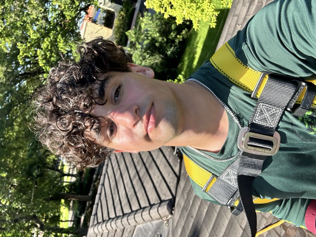 Michael Babun taking a selfie on a tile roof, wearing his yellow safety harness