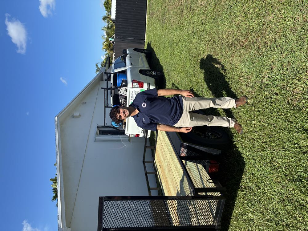 Michael Babun smiling in front of his work trailer and truck